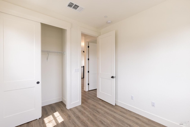 unfurnished bedroom featuring a closet, visible vents, light wood-type flooring, and baseboards