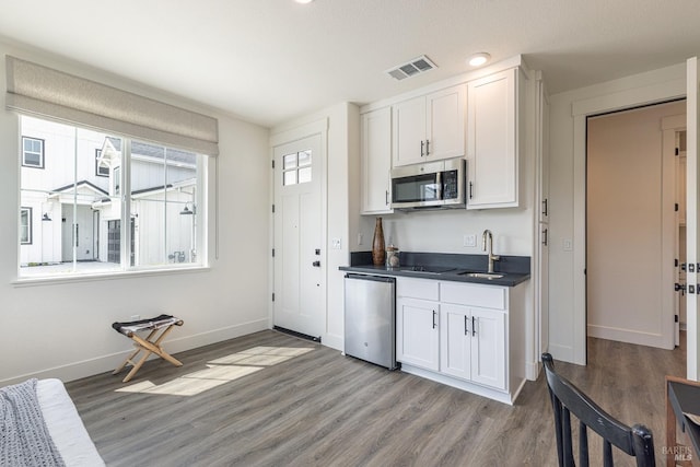kitchen featuring white cabinets, visible vents, dark countertops, a sink, and stainless steel appliances