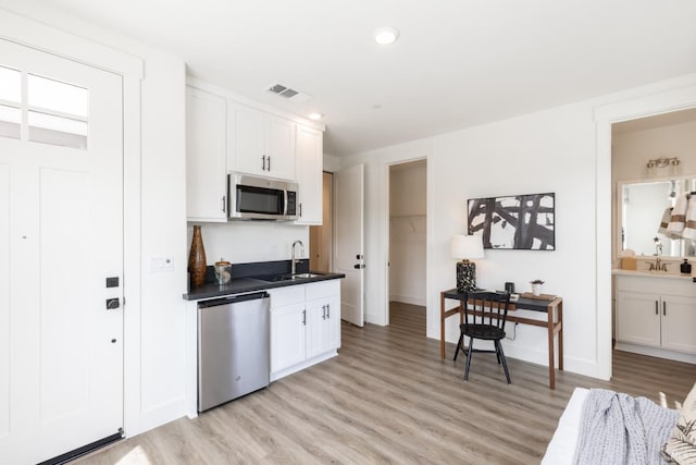 kitchen featuring dishwashing machine, white cabinetry, visible vents, stainless steel microwave, and dark countertops