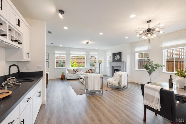 living room featuring light wood-style floors, a fireplace, visible vents, recessed lighting, and baseboards