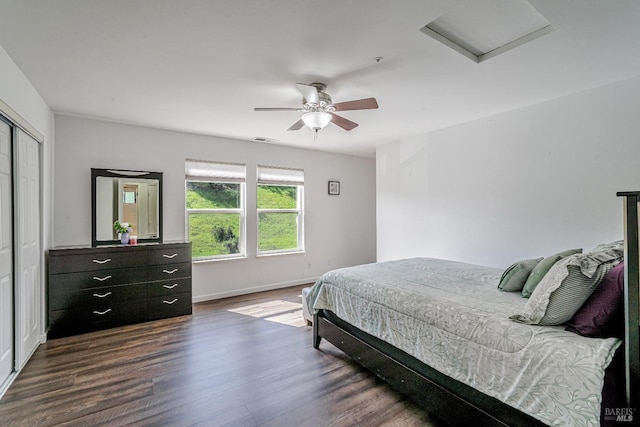 bedroom with visible vents, baseboards, dark wood-style flooring, ceiling fan, and attic access