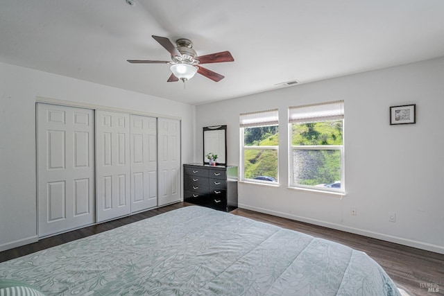 bedroom featuring ceiling fan, a closet, visible vents, dark wood-style flooring, and baseboards