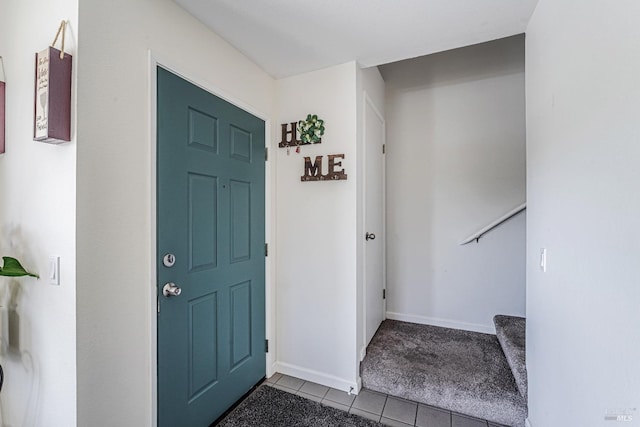 tiled foyer featuring baseboards, carpet flooring, and stairs