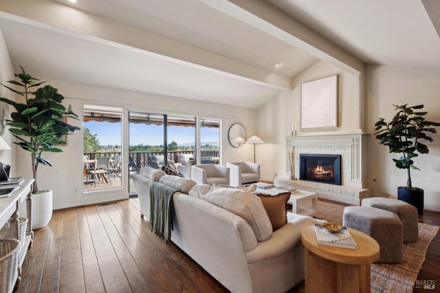 living room featuring baseboards, lofted ceiling with beams, wood-type flooring, and a brick fireplace