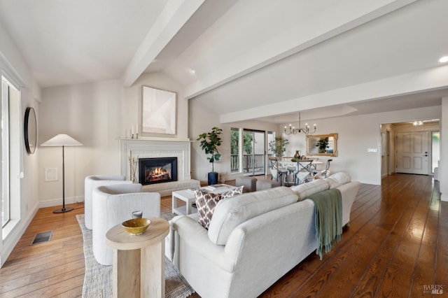 living area with hardwood / wood-style floors, a notable chandelier, vaulted ceiling with beams, and visible vents