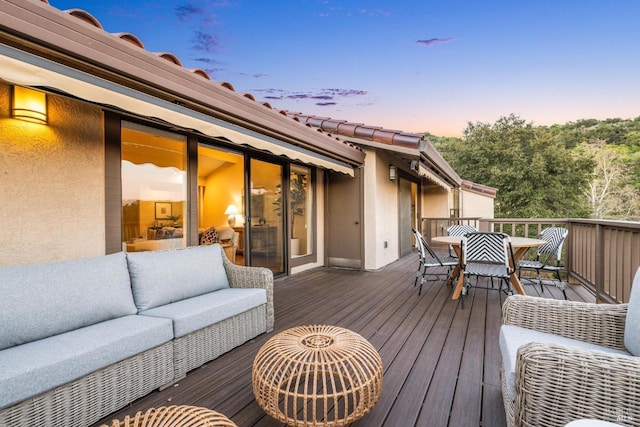 deck at dusk with an outdoor living space and outdoor dining area