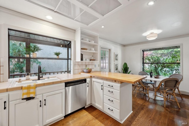 kitchen with stainless steel dishwasher, a sink, crown molding, and wood finished floors