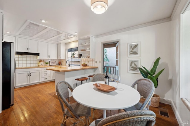 dining room featuring visible vents, baseboards, light wood-type flooring, crown molding, and recessed lighting