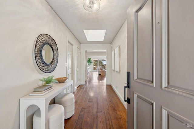 hallway featuring dark wood-style floors, baseboards, and a skylight