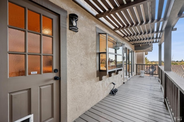 doorway to property with a pergola, stucco siding, and a balcony