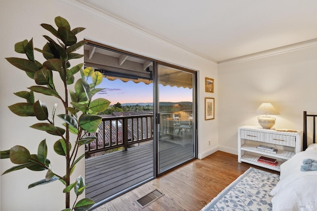 interior space featuring visible vents, baseboards, ornamental molding, wood finished floors, and access to exterior
