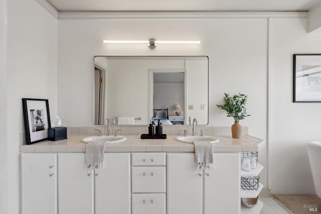 ensuite bathroom with a sink, double vanity, ensuite bath, and crown molding