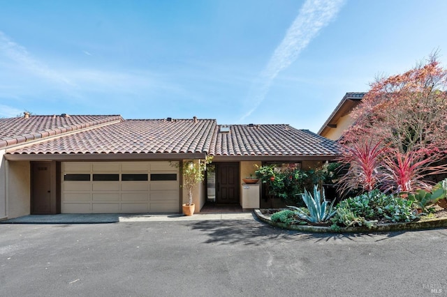 view of front of property with driveway, a tiled roof, an attached garage, and stucco siding