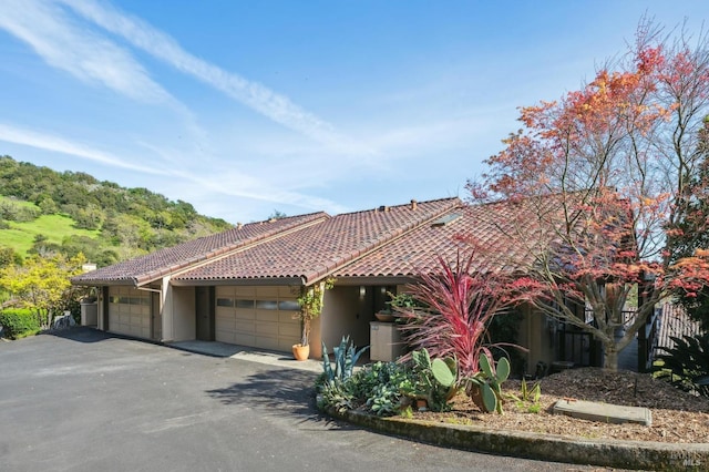 view of front facade featuring a tile roof, an attached garage, driveway, and stucco siding