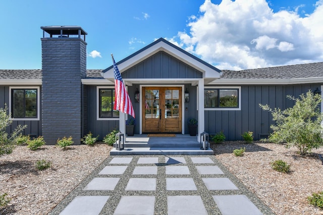 view of front facade with a chimney, french doors, board and batten siding, and roof with shingles