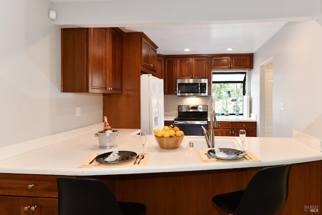 kitchen featuring a sink, a breakfast bar area, appliances with stainless steel finishes, and a peninsula
