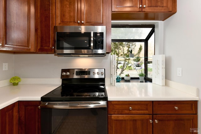 kitchen featuring light countertops, stainless steel microwave, and range with electric stovetop