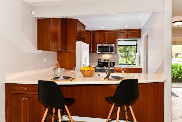 kitchen with light countertops, a breakfast bar, a peninsula, and stainless steel appliances