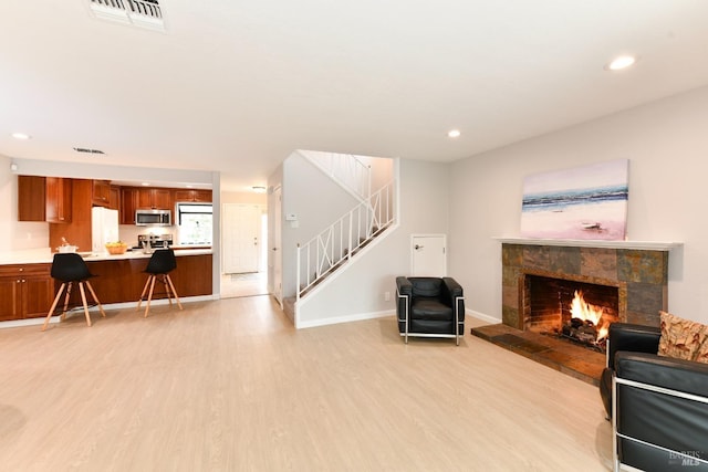 living area with visible vents, light wood-style flooring, recessed lighting, and stairs