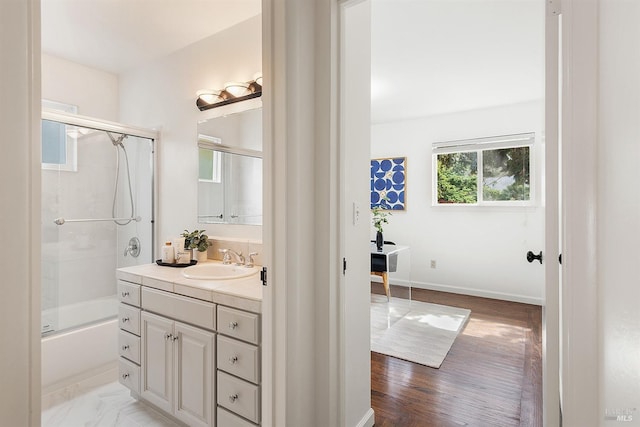bathroom featuring combined bath / shower with glass door, vanity, and baseboards
