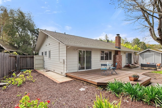 back of house with a chimney, a fenced backyard, an outdoor structure, a wooden deck, and roof with shingles