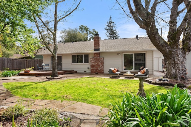 back of house featuring a shingled roof, a deck, a yard, a chimney, and fence
