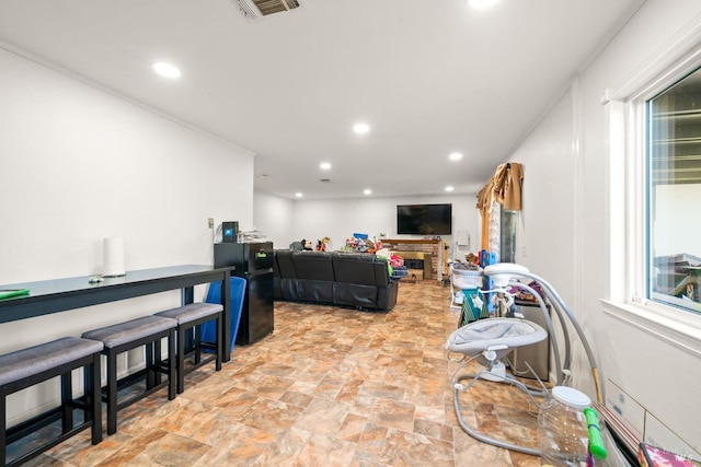 living area featuring stone finish flooring, recessed lighting, visible vents, and a healthy amount of sunlight
