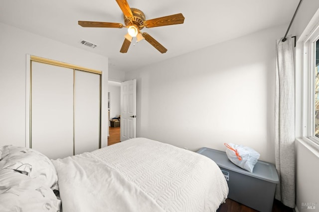 bedroom featuring ceiling fan, visible vents, a closet, and dark wood finished floors
