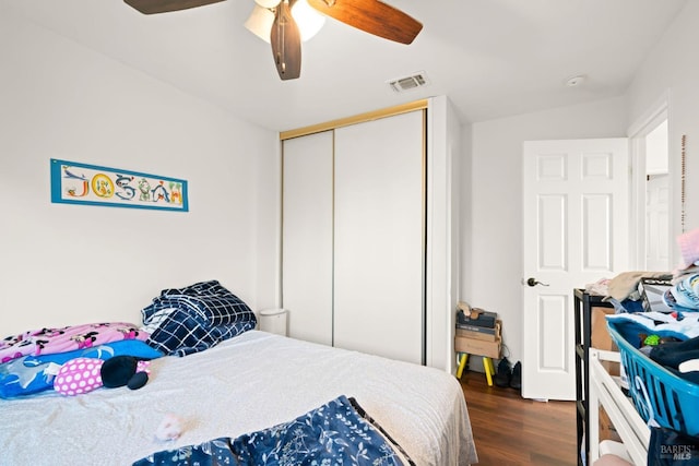 bedroom featuring dark wood-type flooring, visible vents, ceiling fan, and a closet