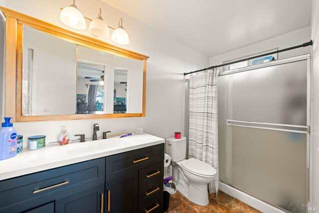 bathroom with toilet, a stall shower, vanity, and ceiling fan