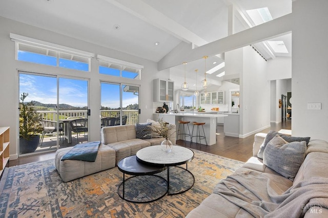 living room with baseboards, beamed ceiling, dark wood-type flooring, a skylight, and high vaulted ceiling