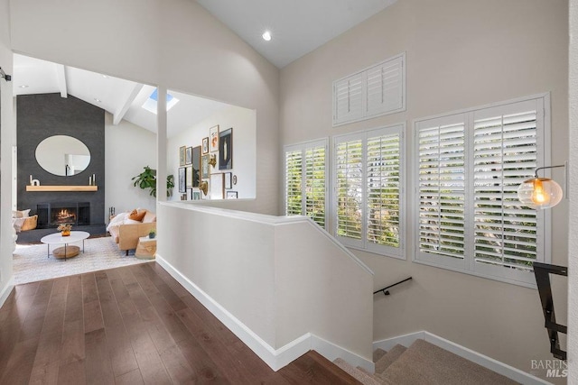 corridor with wood finished floors, high vaulted ceiling, baseboards, and beamed ceiling