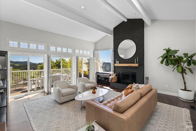 living area with high vaulted ceiling, beamed ceiling, a large fireplace, baseboards, and hardwood / wood-style flooring