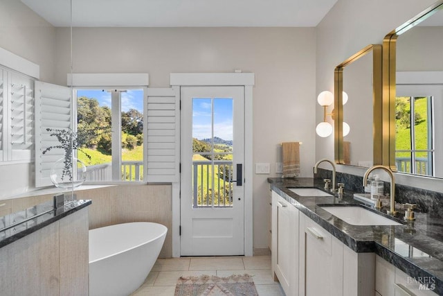 bathroom with a sink, tile patterned floors, double vanity, and a freestanding tub