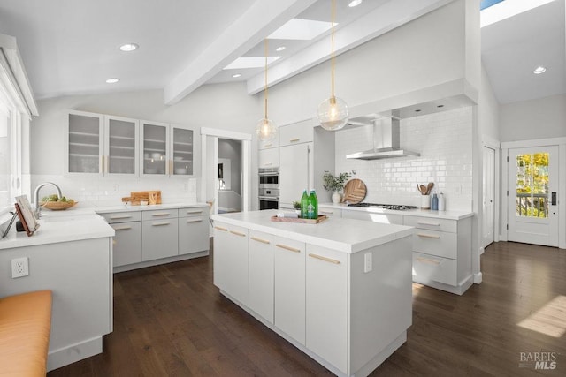 kitchen featuring lofted ceiling with beams, wall chimney range hood, a kitchen island, dark wood-type flooring, and gas stovetop
