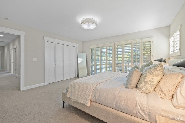 carpeted bedroom featuring a closet and baseboards
