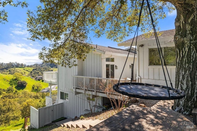 view of side of home featuring a balcony, board and batten siding, and a shingled roof