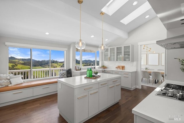 kitchen featuring a skylight, white cabinetry, dark wood-type flooring, decorative backsplash, and stainless steel gas stovetop