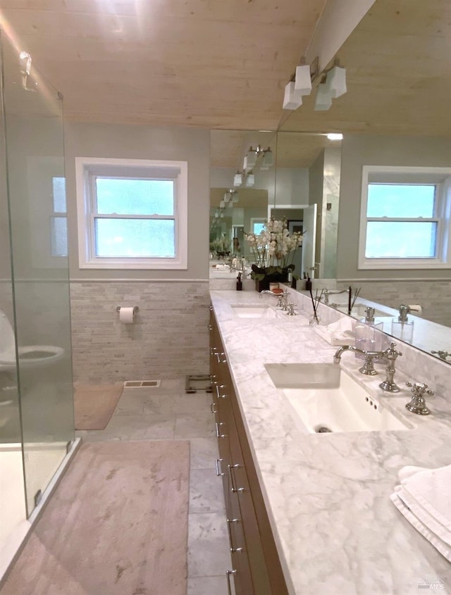 bathroom featuring double vanity, visible vents, a stall shower, and a sink