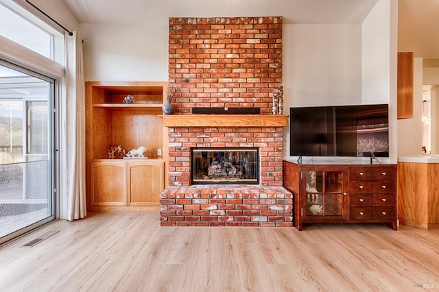 living area featuring a fireplace, visible vents, and wood finished floors