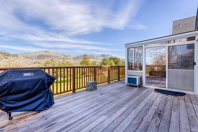 wooden deck featuring a mountain view, grilling area, and a sunroom