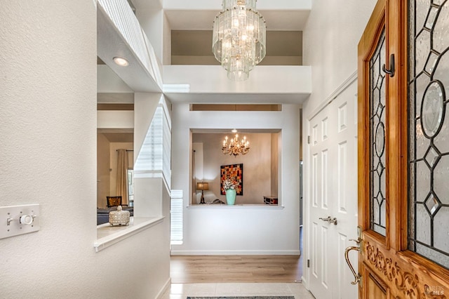 foyer with baseboards, an inviting chandelier, and wood finished floors