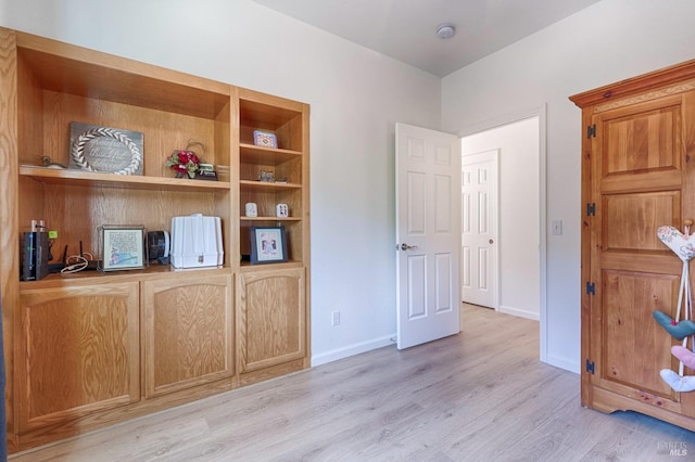 unfurnished office with built in features, baseboards, and light wood-style floors