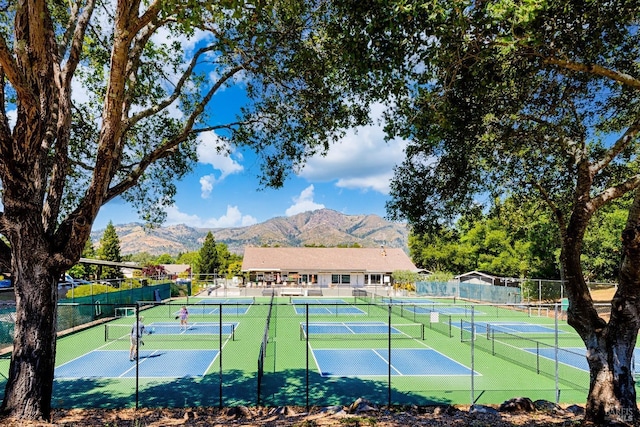 view of sport court with a mountain view and fence