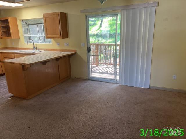 19557 Donkey Hill Rd, Hidden Valley Lake, CA 95467 - kitchen featuring a sink, light countertops, a breakfast bar, a peninsula, and light colored carpet