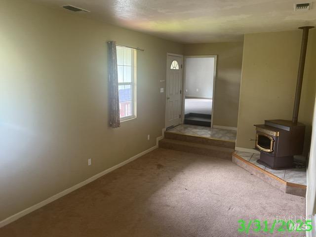 19557 Donkey Hill Rd, Hidden Valley Lake, CA 95467 - unfurnished living room featuring a wood stove, carpet, visible vents, and baseboards