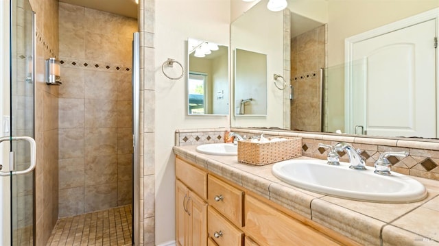 full bathroom with double vanity, a shower stall, and a sink