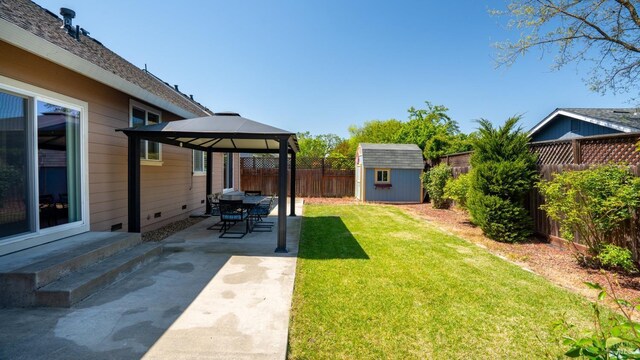 view of yard with a patio, a fenced backyard, a storage unit, a gazebo, and an outbuilding