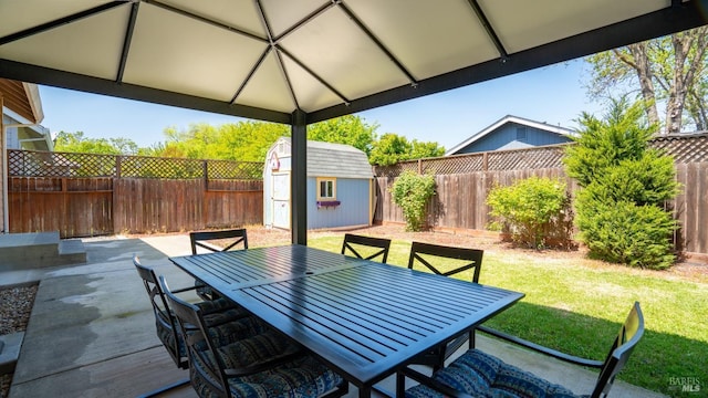 view of patio / terrace featuring a storage shed, an outdoor structure, outdoor dining area, and a fenced backyard