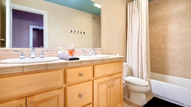 bathroom with a sink, tile patterned floors, toilet, and double vanity